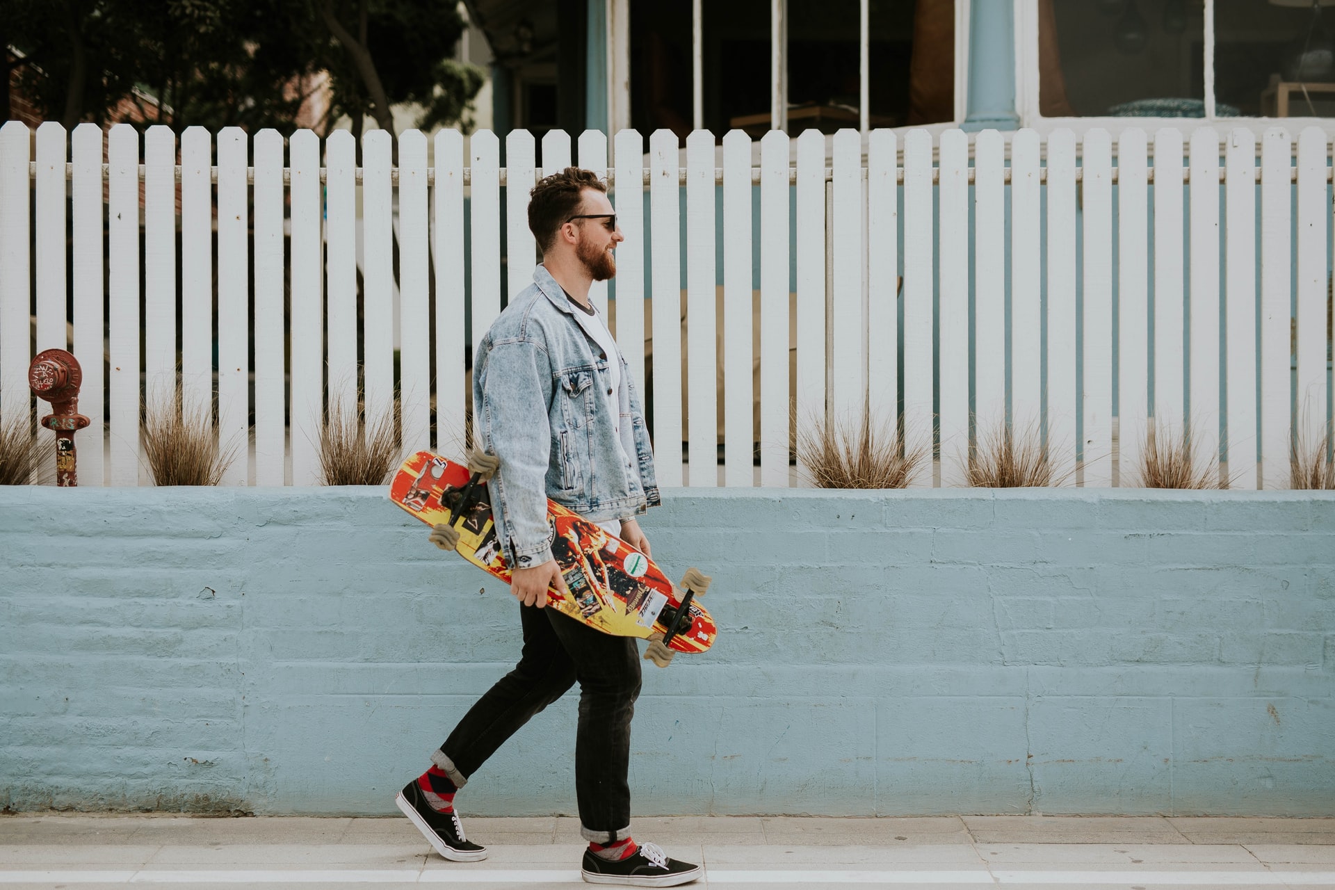 man walking along a street with skateboard