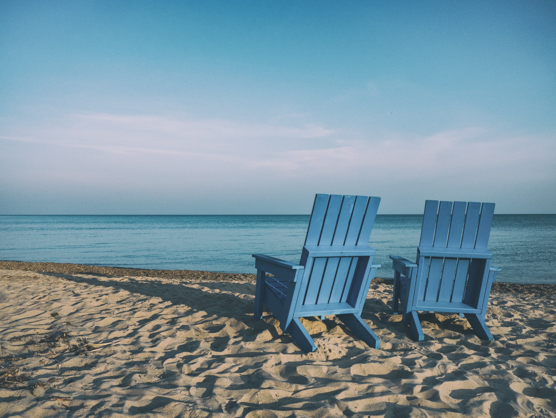 two blue beach chairs in the sand